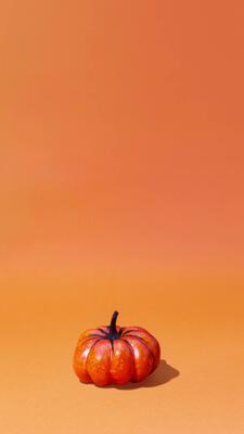 Colorful pumpkins on orange background appear, jump. Stop motion animation  copy space. Vertical banner, happy Halloween