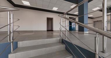 rotation and panoramic view on emergency stairs in empty modern hall with columns, doors and panoramic windows overlooking the city. video