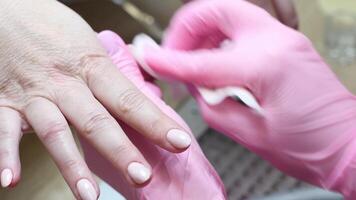 master carries out the final processing of the client's nails in the beauty salon and removes excess dust with a paper napkin, video