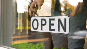 Closed. Hanging sign on a storefront window. Employee changes the plate from Open to Closed video