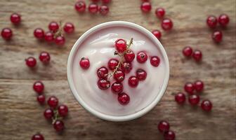 Yogurt with red currant berries on wooden table with copy space, top view photo