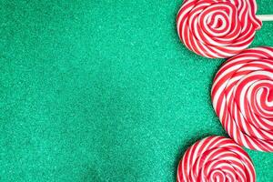 Three Christmas lollypops on a green and glitter backdrop. Wallpaper for Christmas with copy space for text. photo