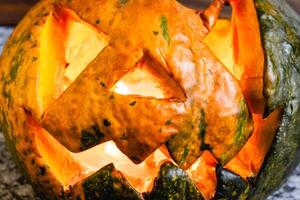 A small homemade Halloween pumpkin with a candle inside. On a dark background. photo