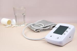 Digital blood pressure tonometer and pack of pills on a light background with copy space. photo