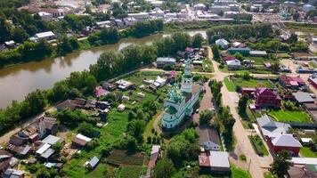 Top view of beautiful church in town by river in summer. Clip. Old colorful church in town by river on sunny day. Beautiful landscape of town with river and ancient churches in summer video