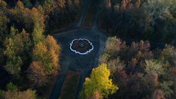Top view of fountain and roads in autumn forest. Clip. Roads intersect in center with fountain. Crossroads with fountain in autumn forest on cloudy day video