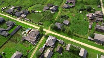 Top view of rustic cottages with green fields. Stock footage. Neat plots of village houses with green fields. Green plots with houses in cottage village in summer video
