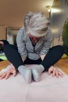 A group of senior women engage in various yoga exercises, including neck, back, and leg stretches, under the guidance of a trainer in a sunlit space, promoting well-being and harmony photo