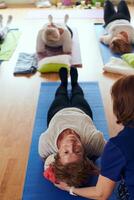 Top view of group of senior women engage in various yoga exercises, including neck, back, and leg stretches, under the guidance of a trainer in a sunlit space, promoting well-being and harmony photo
