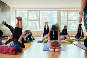 A group of senior women engage in various yoga exercises, including neck, back, and leg stretches, under the guidance of a trainer in a sunlit space, promoting well-being and harmony photo