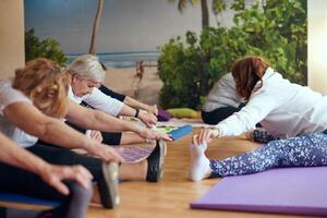 A group of senior women engage in various yoga exercises, including neck, back, and leg stretches, under the guidance of a trainer in a sunlit space, promoting well-being and harmony photo