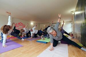 A group of senior women engage in various yoga exercises, including neck, back, and leg stretches, under the guidance of a trainer in a sunlit space, promoting well-being and harmony photo