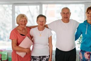 A group of seniors and one man happily pose with their yoga instructor after a successful training session. photo