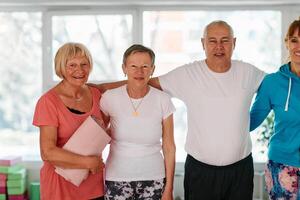A group of seniors and one man happily pose with their yoga instructor after a successful training session. photo