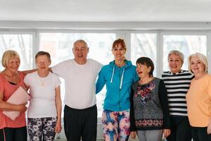 A group of seniors and one man happily pose with their yoga instructor after a successful training session. photo