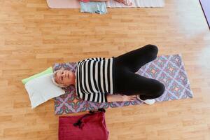 Senior woman practicing stretching and meditation on the floor, focusing on proper alignment and relaxation. photo