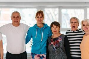 A group of seniors and one man happily pose with their yoga instructor after a successful training session. photo
