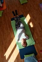 Senior woman practicing stretching and meditation on the floor, focusing on proper alignment and relaxation. photo