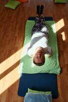 Senior woman practicing stretching and meditation on the floor, focusing on proper alignment and relaxation. photo