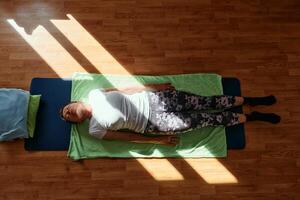 Senior woman practicing stretching and meditation on the floor, focusing on proper alignment and relaxation. photo