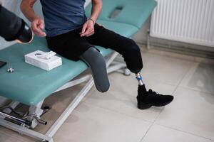 Man with prosthetic leg sitting on examination table photo