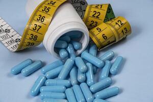 bottle of pills, some of which spilled onto a light blue surface photo