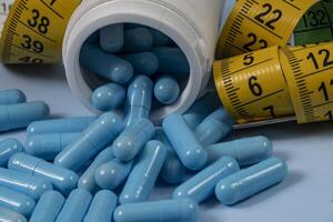 bottle of pills, some of which spilled onto a light blue surface photo