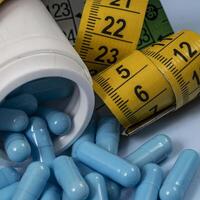 bottle of pills, some of which spilled onto a light blue surface photo