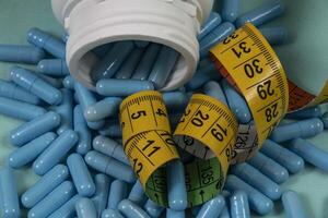 bottle of pills, some of which spilled onto a light blue surface photo