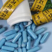 bottle of pills, some of which spilled onto a light blue surface photo
