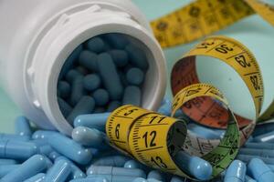 bottle of pills, some of which spilled onto a light blue surface photo