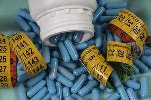 bottle of pills, some of which spilled onto a light blue surface photo