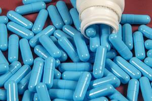 blue medicine capsules and white bottle photo