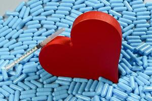 heart shape and medicine capsules representing heart problems and treatment photo