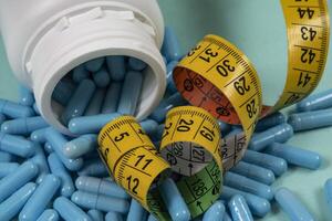 bottle of pills, some of which spilled onto a light blue surface photo
