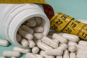 bottle of pills, some of which spilled onto a light blue surface photo