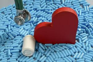 heart shape and medicine capsules representing heart problems and treatment photo