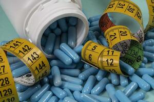 bottle of pills, some of which spilled onto a light blue surface photo
