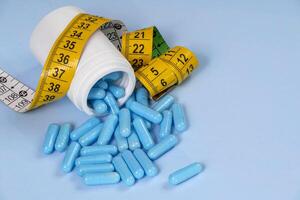 bottle of pills, some of which spilled onto a light blue surface photo