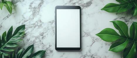 A modern digital device mockup featuring smartphone surrounded by lush green leaves on marble surface, creating fresh and vibrant atmosphere. photo