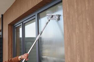 Rubber squeegee cleans a soaped window. photo