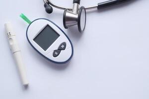 Diabetes Management Tools Glucometer and Stethoscope Displayed on a White Background Surface photo