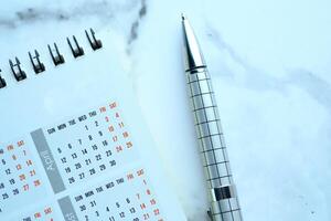 An Elegant Calendar with a Stylish Pen on a Marble Surface, Ideal for Efficient Planning photo