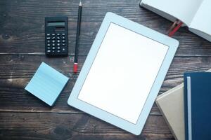 Minimalistic Workspace with Tablet, Calculator, and Notepad on Rustic Wooden Table photo