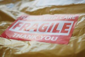 deliver packet marked with a caution label for fragile goods handling during shipping photo