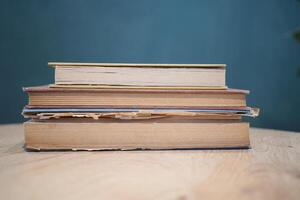 An open book with its pages gently turning rests on a wooden table in the breeze photo