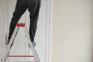 A person is standing safely on a ladder while working on a home improvement project photo