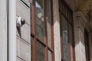 A surveillance camera has been installed on the exterior of the building featuring reflections photo