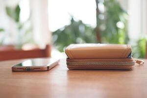 A Stylish Wallet and a Smartphone beautifully displayed on a Wooden Table surface photo