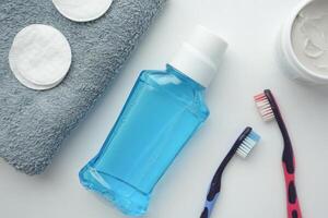 mouthwash liquid in a container and toothbrush on white background photo